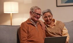 Seniorzy kobieta i mężczyzna siedzący na kanapie z laptopem