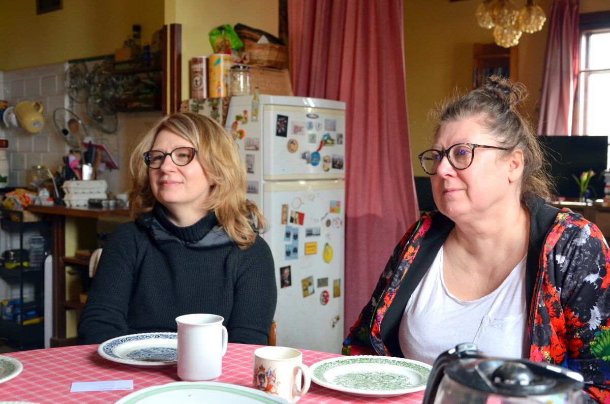 Siedzą przy stole podczas rozmowy Magda Karpińska i Anna Gaik, w tle lodówka i pomieszczenie kuchnenne